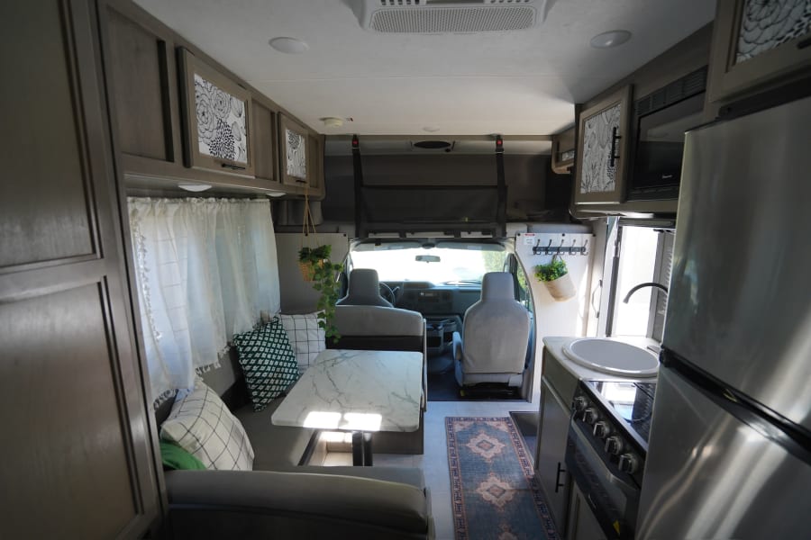 Inside a modern **rv rental**, featuring a full kitchen, dining table, cozy seating, and front cabin views.