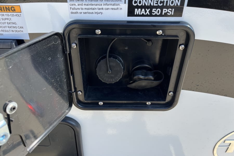 RV rental water utility panel with open access. Details for potable water fill, city water connection (Max 50 PSI), and safety warnings.