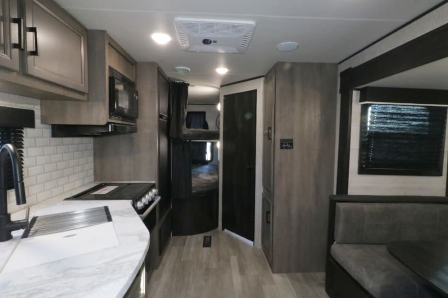 Spacious RV rental interior with a fully equipped kitchen, comfortable dinette seating, and dedicated bunk beds.