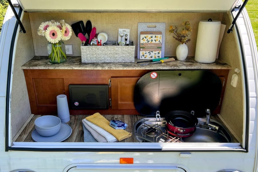 Compact & convenient RV rental outdoor kitchen, fully stocked with sink, stove, utensils, dishes, and accessories.