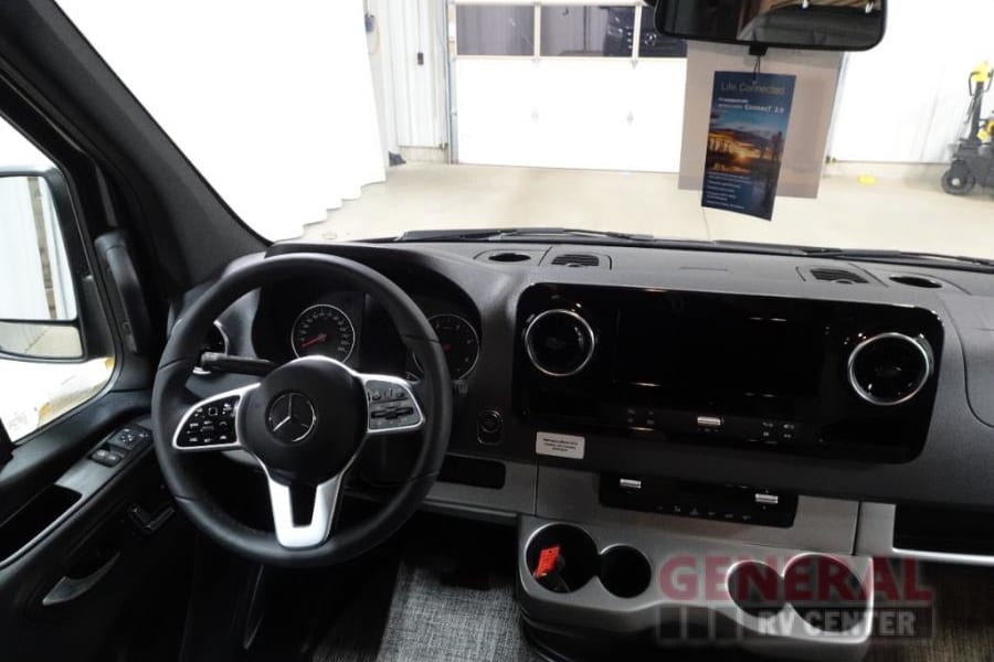 RV rental interior: Mercedes-Benz Sprinter cockpit with dashboard, steering wheel, and infotainment. Modern, ready for your trip.