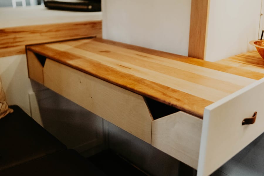 RV rental: A clever light wood pull-out desk with an open storage drawer and cozy bench seating maximizes this camper's space.