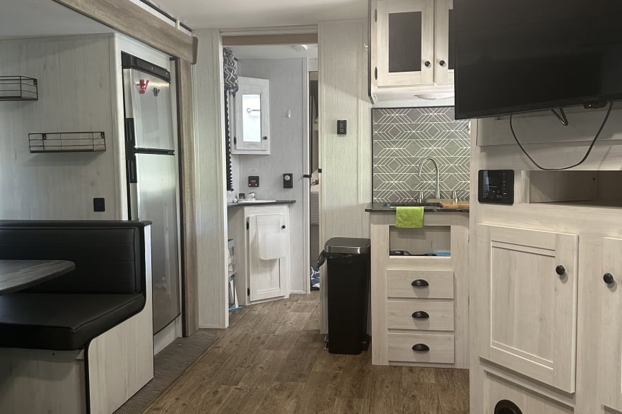 Spacious RV rental interior featuring a modern kitchen, dinette, and wood-look flooring for comfortable mobile living.