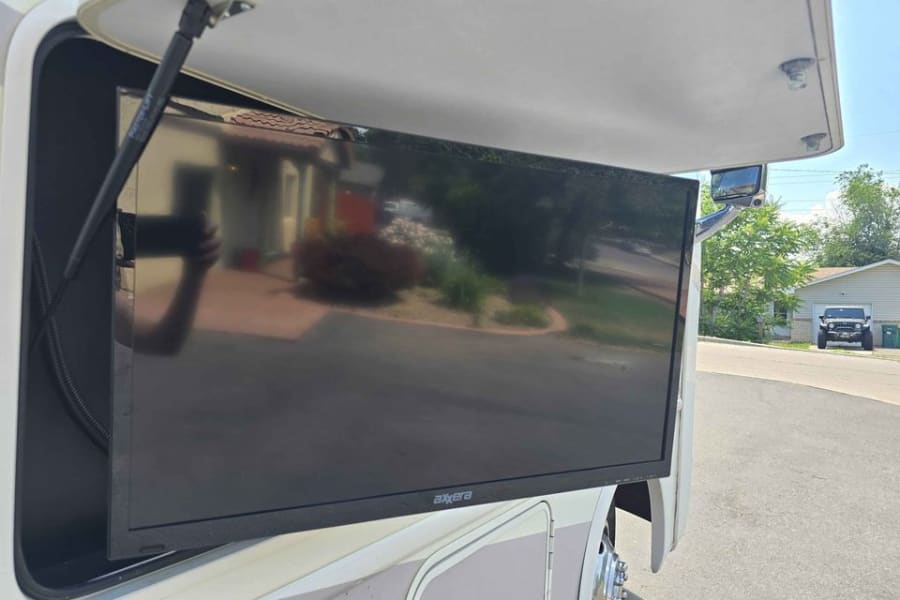 Outdoor TV mounted on an RV rental, pulled out for viewing. A convenient feature for outdoor leisure.