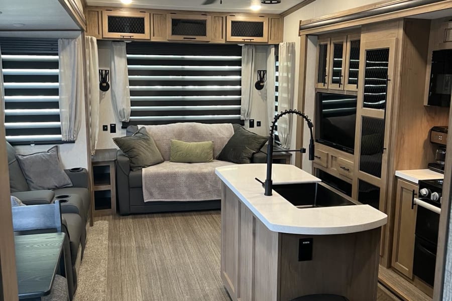 Spacious RV rental interior: living room, kitchen island, and dining area. Modern design with cozy feel.