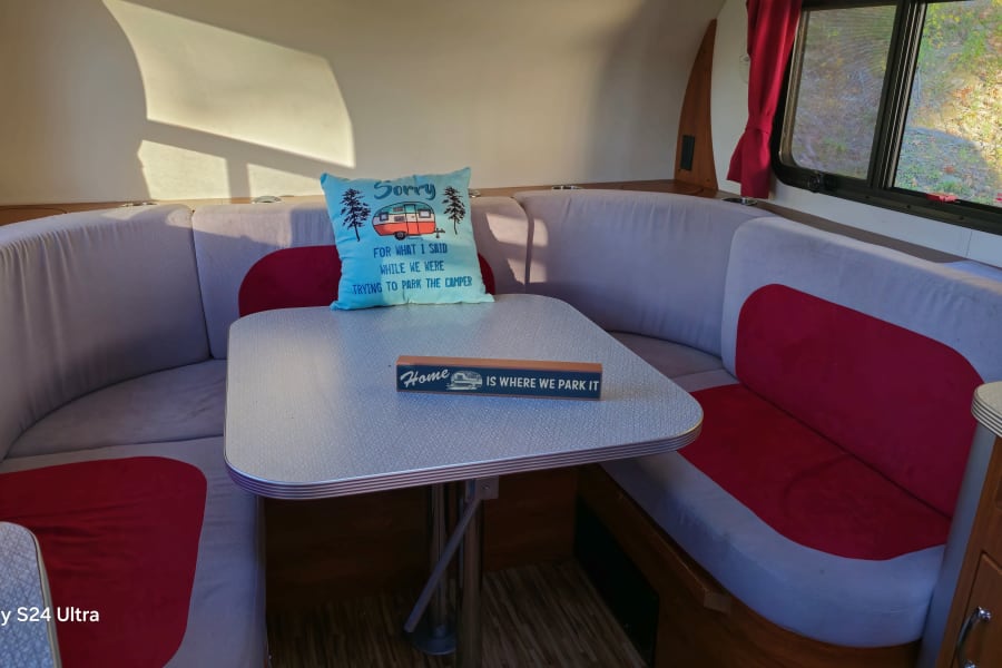 Cozy RV rental dinette with a fun "Sorry for parking" pillow & "Home is where we park it" sign.