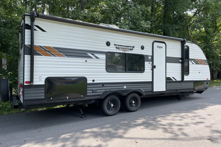 Bright, modern white & grey travel trailer, a Forest River Wildwood Lite RV, parked outdoors. Great for an RV rental vacation.