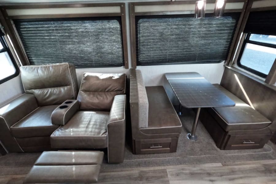 RV rental: plush interior featuring comfortable recliners (one extended) and a compact dinette.