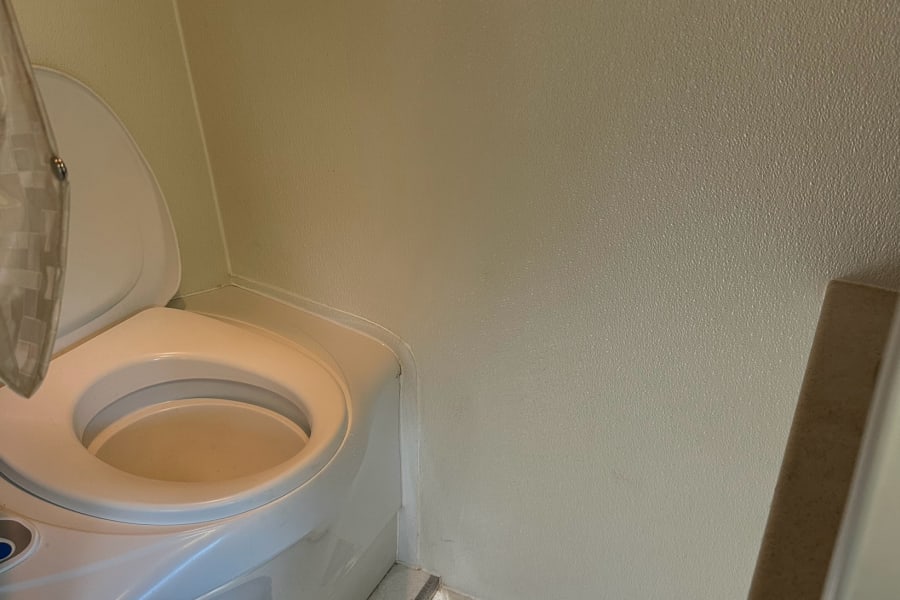 RV rental: Compact bathroom with a white toilet and integrated shower base. Walls are light-colored.