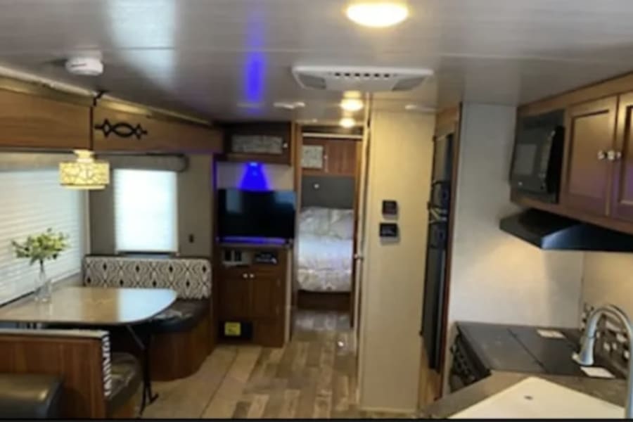Inside this modern rv rental: a well-equipped kitchen, comfortable dinette, and cozy bedroom. Ideal travel trailer for your next trip.