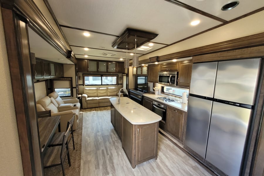 Modern rv rental interior showcasing a full kitchen with island and stainless steel appliances, plus a comfy living area.