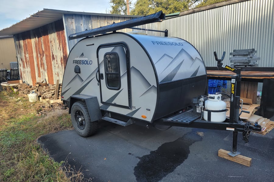 A sleek Freesolo teardrop camper, ideal for an rv rental adventure, is parked with its Thule awning ready.