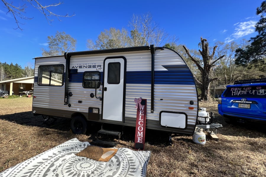 This RV rental travel trailer is set up for a comfortable outdoor camping experience under a clear blue sky.