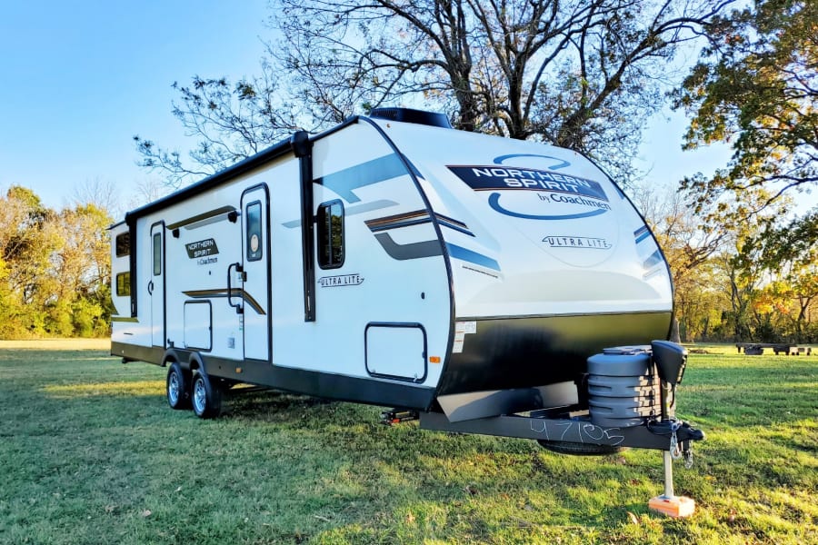 Northern Spirit Ultra Lite travel trailer rv rental, parked in a sunny grassy field ready for adventure.