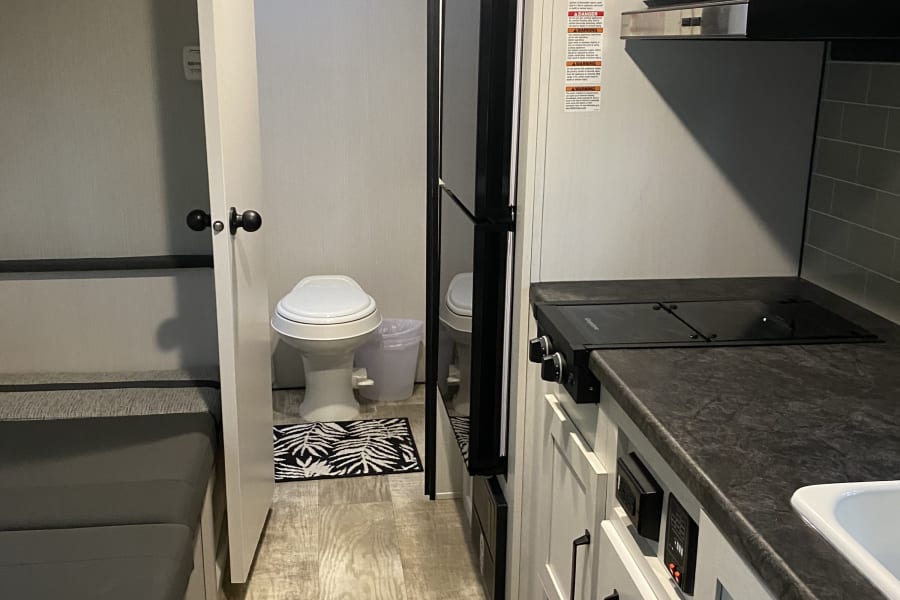 RV rental interior: Right side has a full kitchen, central is a fridge & bathroom, left is seating/bedding. Cozy setup!