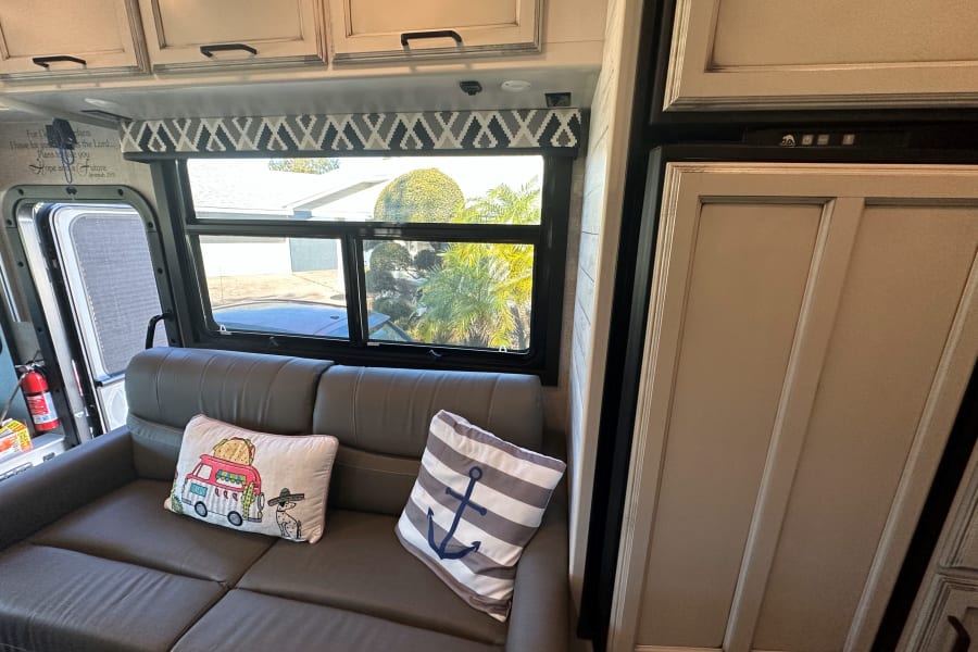 Cozy rv rental interior featuring a comfy sofa with decorative pillows, large window views, and accessible cabinets.