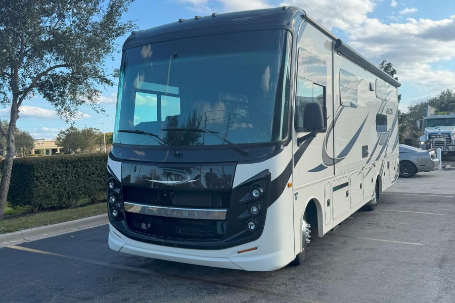 Front view of a modern white Integra Vision RV parked in a lot, ideal for your next RV rental.