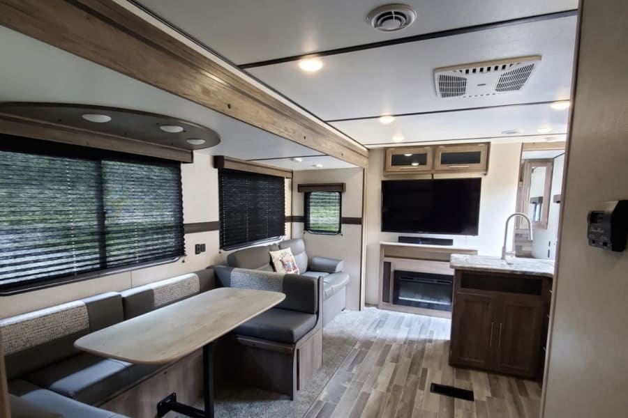 Stylish RV rental interior with a spacious dinette, living area featuring TV/fireplace, and a functional kitchen.