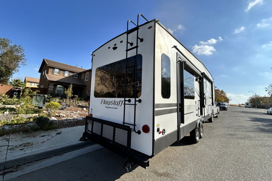 Rear view of a white Flagstaff Super Lite travel trailer, parked on a residential street for RV rental.