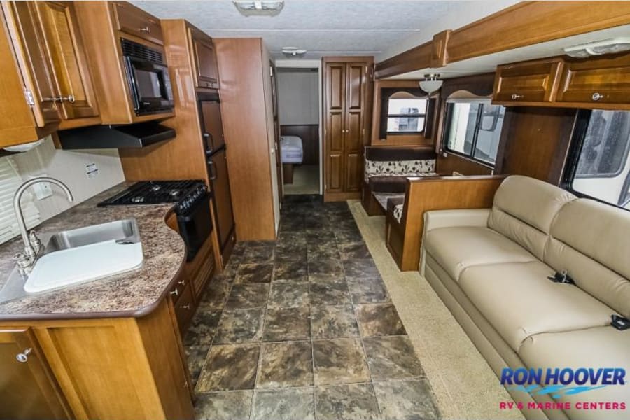 Spacious RV rental interior featuring a kitchen with stove/sink, sofa, and dinette. Ideal for travel.