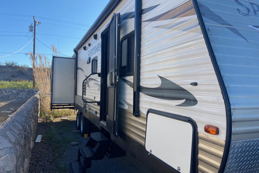 Side view of a spacious RV rental, parked with its door and storage compartment open, ready for outdoor adventures.
