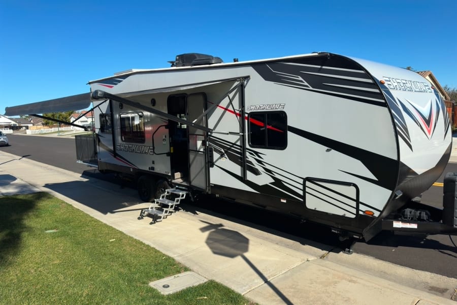 Modern Shockwave toy hauler RV rental with extended awning and convenient steps, ready for your next adventure.