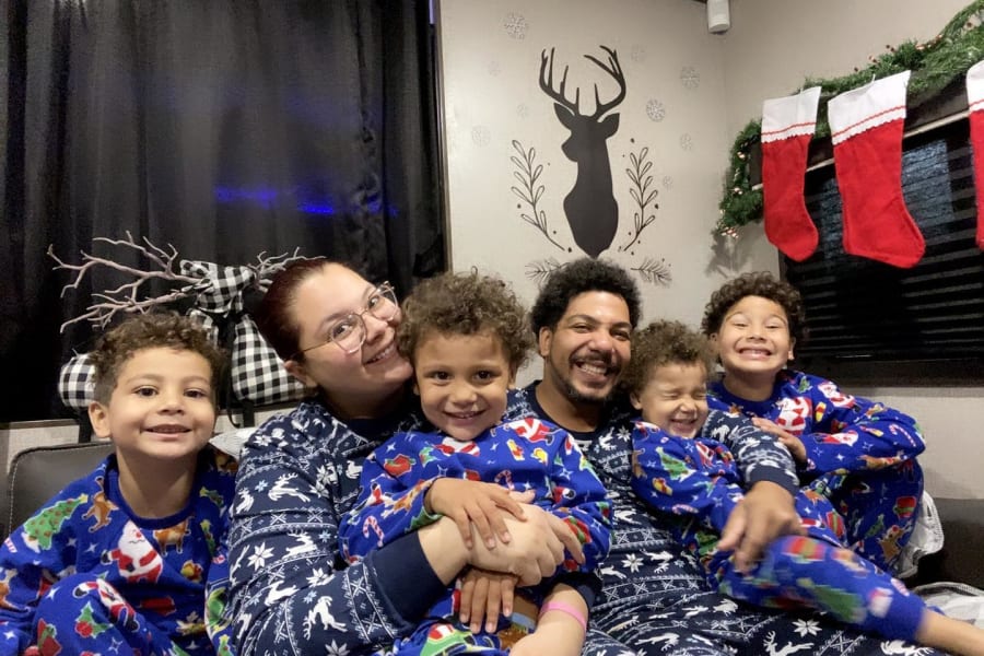 Happy family of six in matching Christmas pajamas in a festive RV rental, surrounded by holiday decorations.