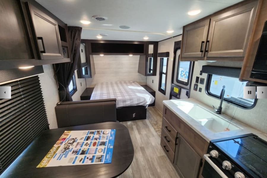RV rental interior: modern design with a kitchen, bed, and dinette. Perfect for your next camper adventure.