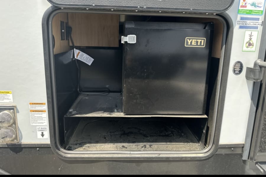RV rental with outdoor amenities: portable Yeti fridge in an exterior compartment, perfect for camping adventures.