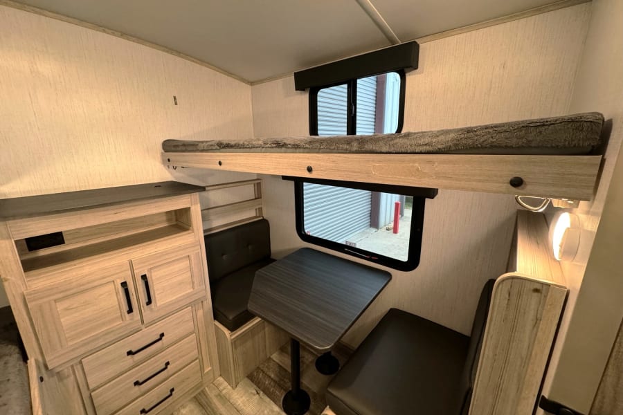 Spacious RV rental bunkhouse interior featuring a comfortable bunk bed, dinette, and ample storage for your next adventure.
