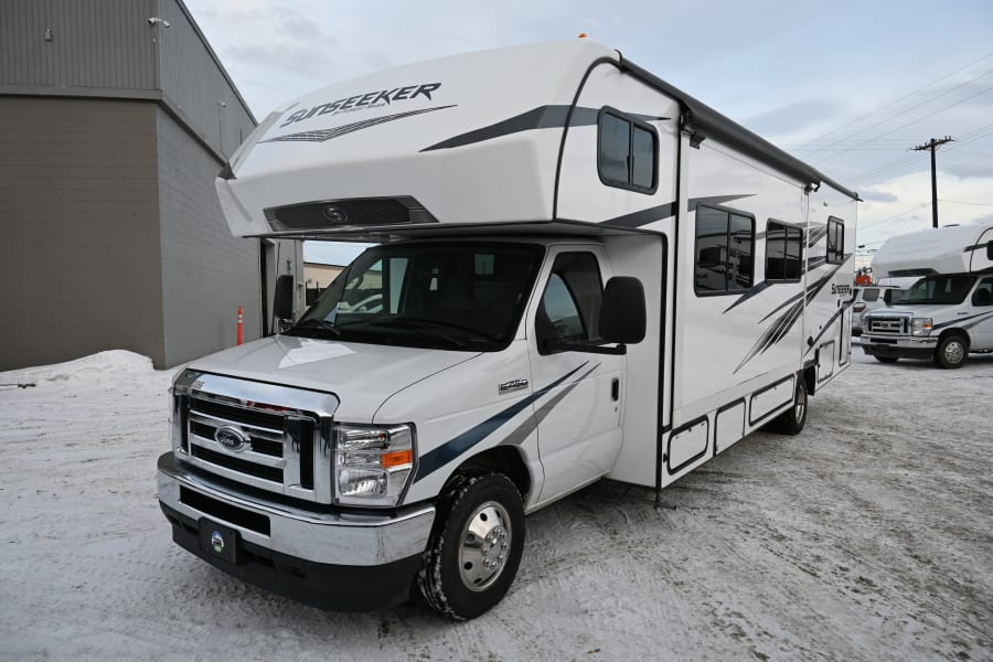 White Sunseeker Class C RV rental parked on a snowy lot, ready for winter trips.