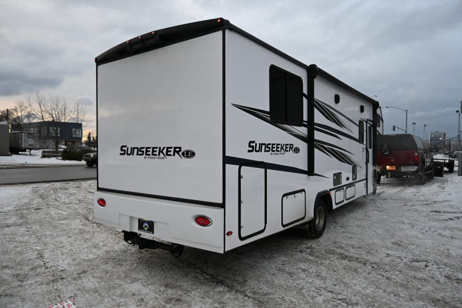 A white Sunseeker RV rental by Forest River, identified by ALASKARVS.COM on its plate, parked on a snowy lot.