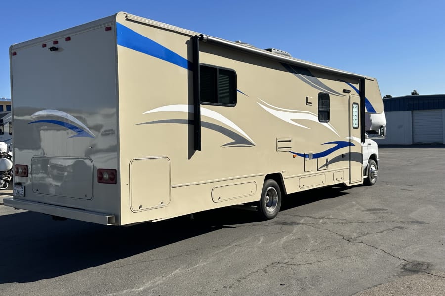 This Class C RV rental, featuring blue and white accents, is ready for adventure on a sunny day.