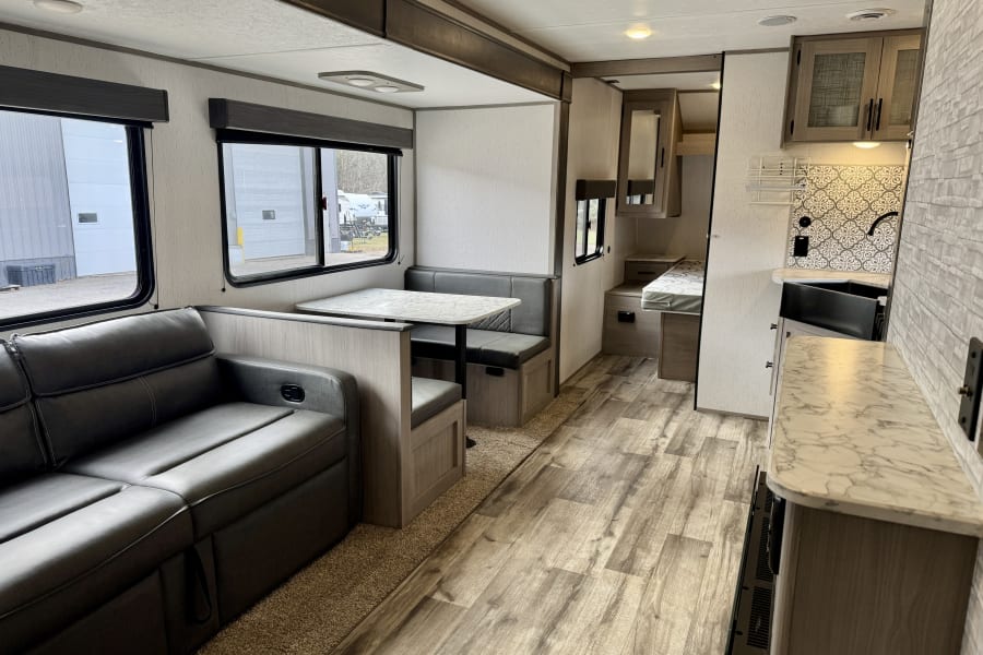 Spacious, modern RV rental interior: a bright living area with sofa, dinette, and equipped kitchen.