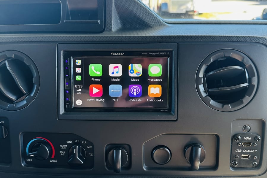 RV rental interior: Pioneer touchscreen with Apple CarPlay for navigation & entertainment, alongside climate controls and USB/HDMI ports.