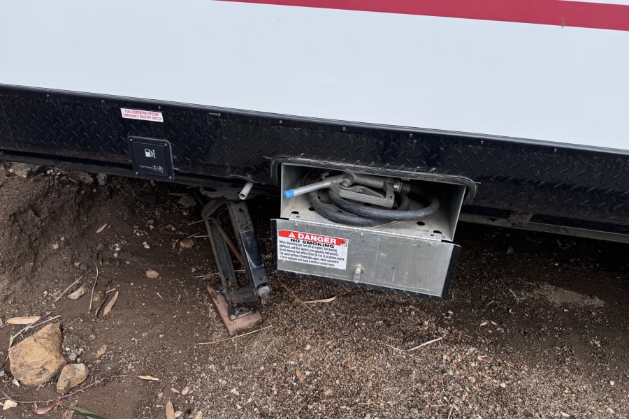 RV rental with an open onboard fuel dispenser, including "No Smoking" and emergency shutoff switch safety warnings.