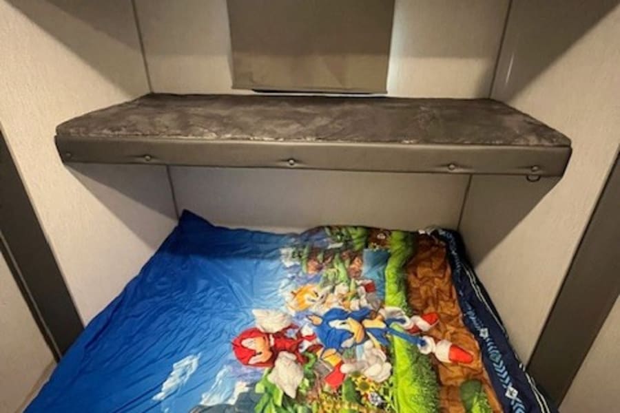 RV rental bunk beds: A cozy space with a Sonic the Hedgehog sleeping bag, perfect for kids.