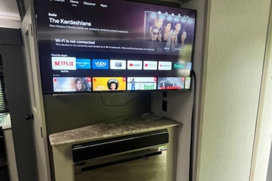 RV rental smart TV setup: Hulu and Netflix apps are visible, but Wi-Fi is not connected, above an electric fireplace.
