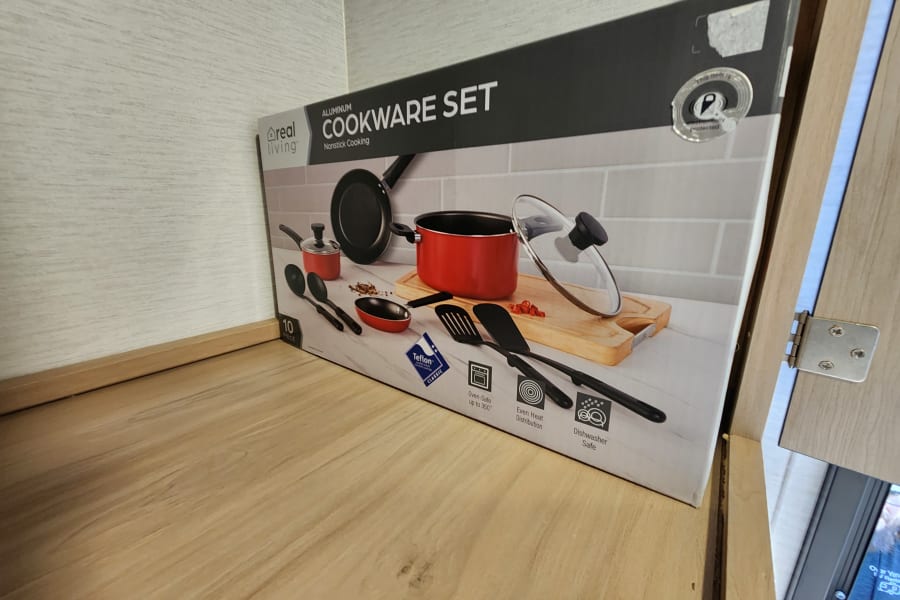 A Real Living Cookware Set box sits in an RV rental kitchen cupboard, ready for your next adventure.