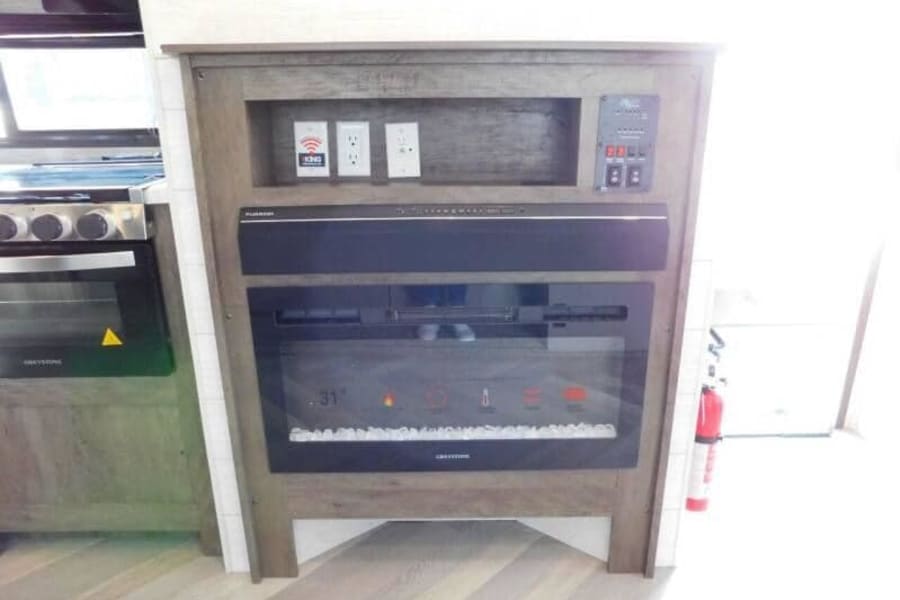 RV rental interior: Greystone oven, electric fireplace, Furrion soundbar, and integrated control panel with outlets.
