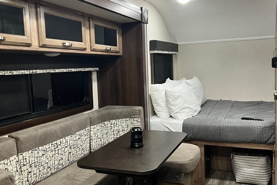 Compact RV rental interior showcasing a modern dinette, bed, and efficient living space for travel.