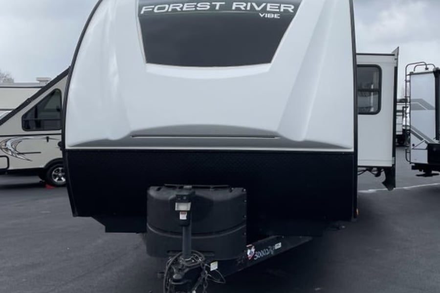White and black Forest River Vibe travel trailer, front view. Explore the open road with an RV rental!