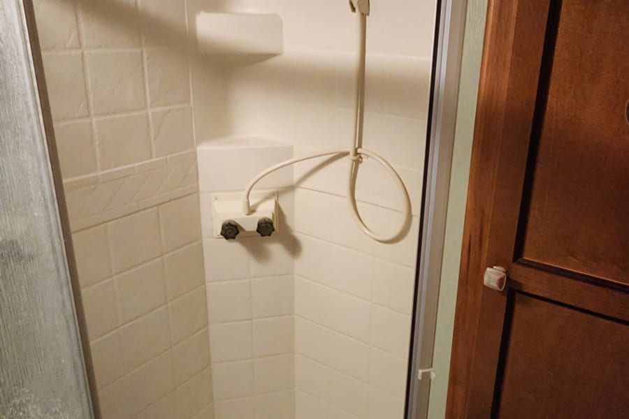 Full interior view of a compact shower within an RV rental, essential for road trip comfort.