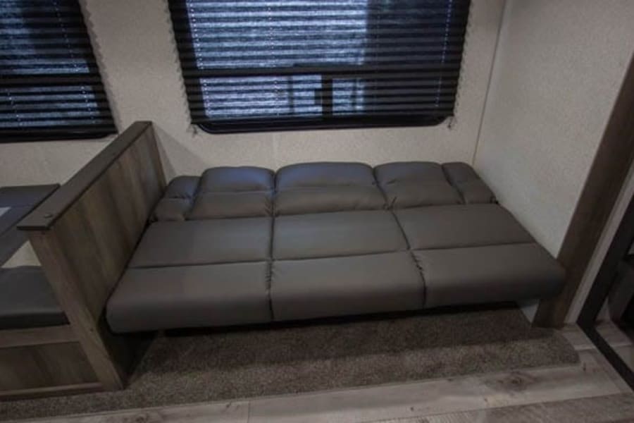 This RV rental features a versatile sofa that converts into a bed, offering comfortable sleeping and seating in a compact living space.
