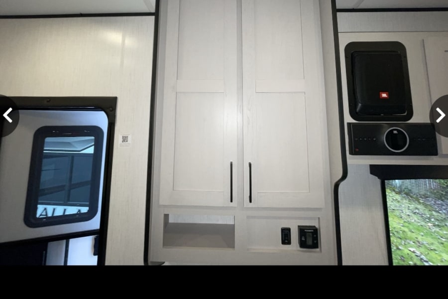 This RV rental's modern interior features light cabinets, open shelving, and a built-in JBL entertainment system.