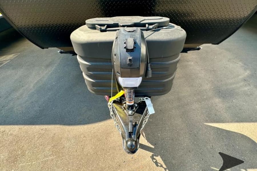 Close-up of an RV rental travel trailer hitch, showing the propane tank cover and electric tongue jack.