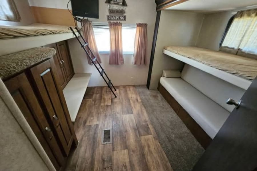 This cozy RV rental features a practical interior with multiple bunk beds, a TV, and comfortable seating areas.