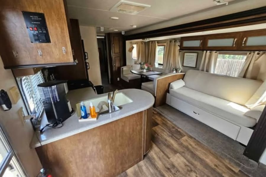 Spacious RV rental interior with a full kitchen, dining booth, and comfy sofa with pull-out storage.