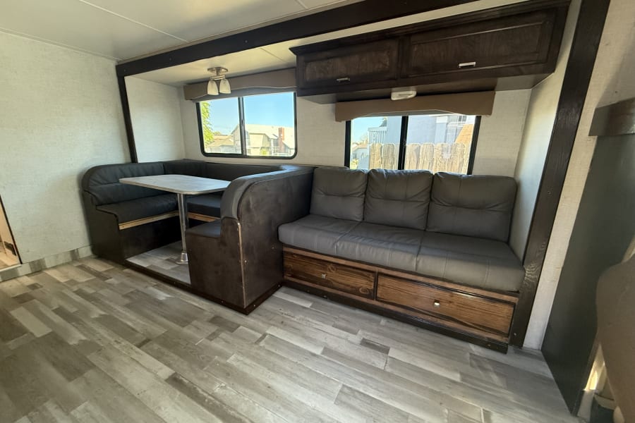 Inside an RV rental: a modern interior featuring a U-shaped dinette, comfy sofa with storage, and overhead cabinets.
