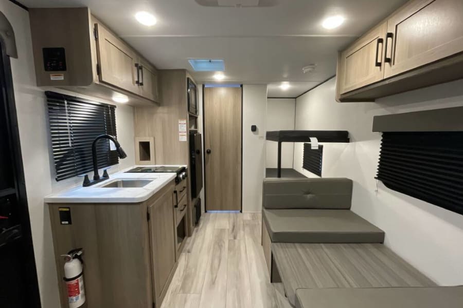 Step inside this rv rental's interior: a compact kitchen, dinette, and bunk beds for family travel adventures.